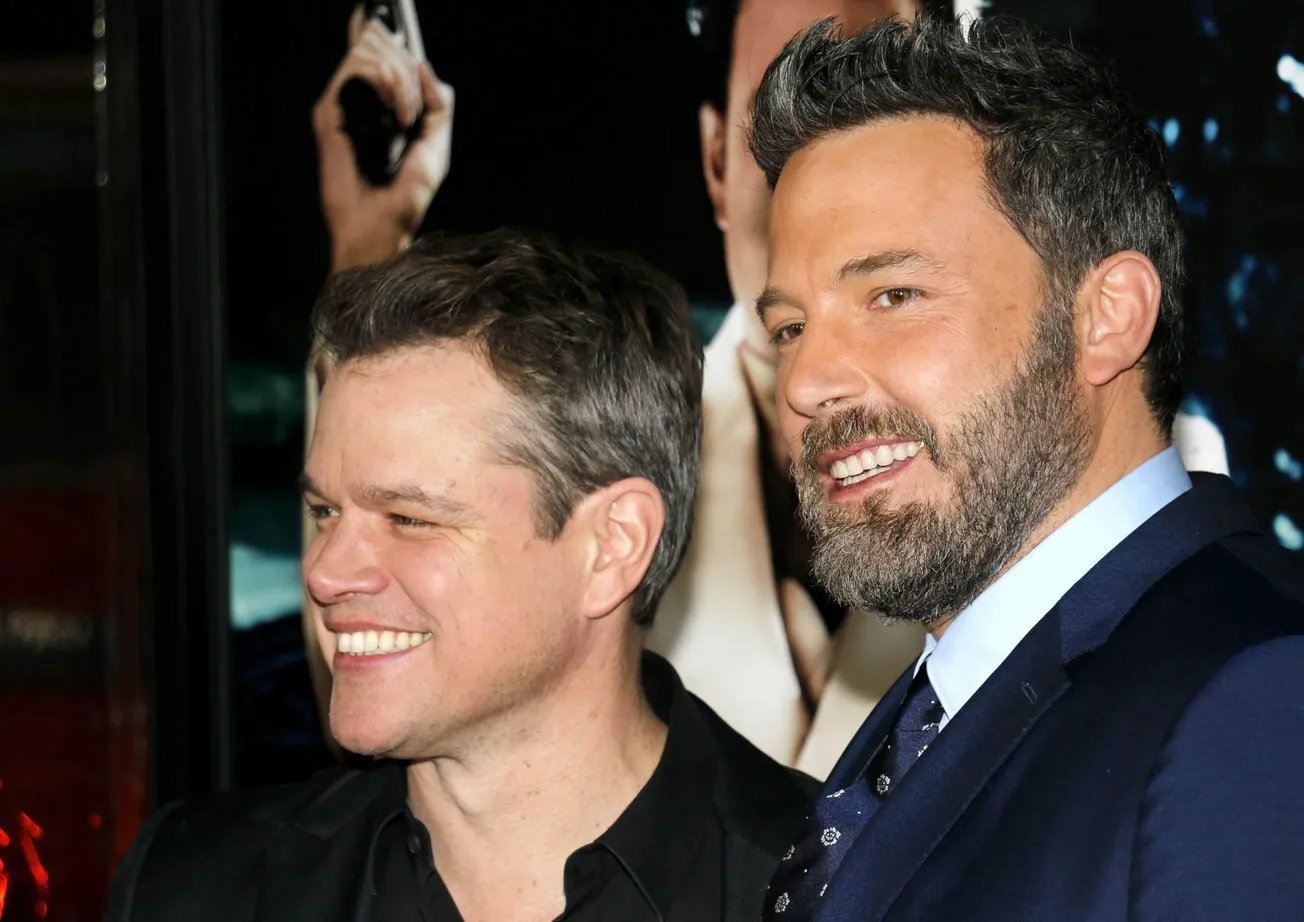 Matt Damon and Ben Affleck smiling together at a red carpet event.
