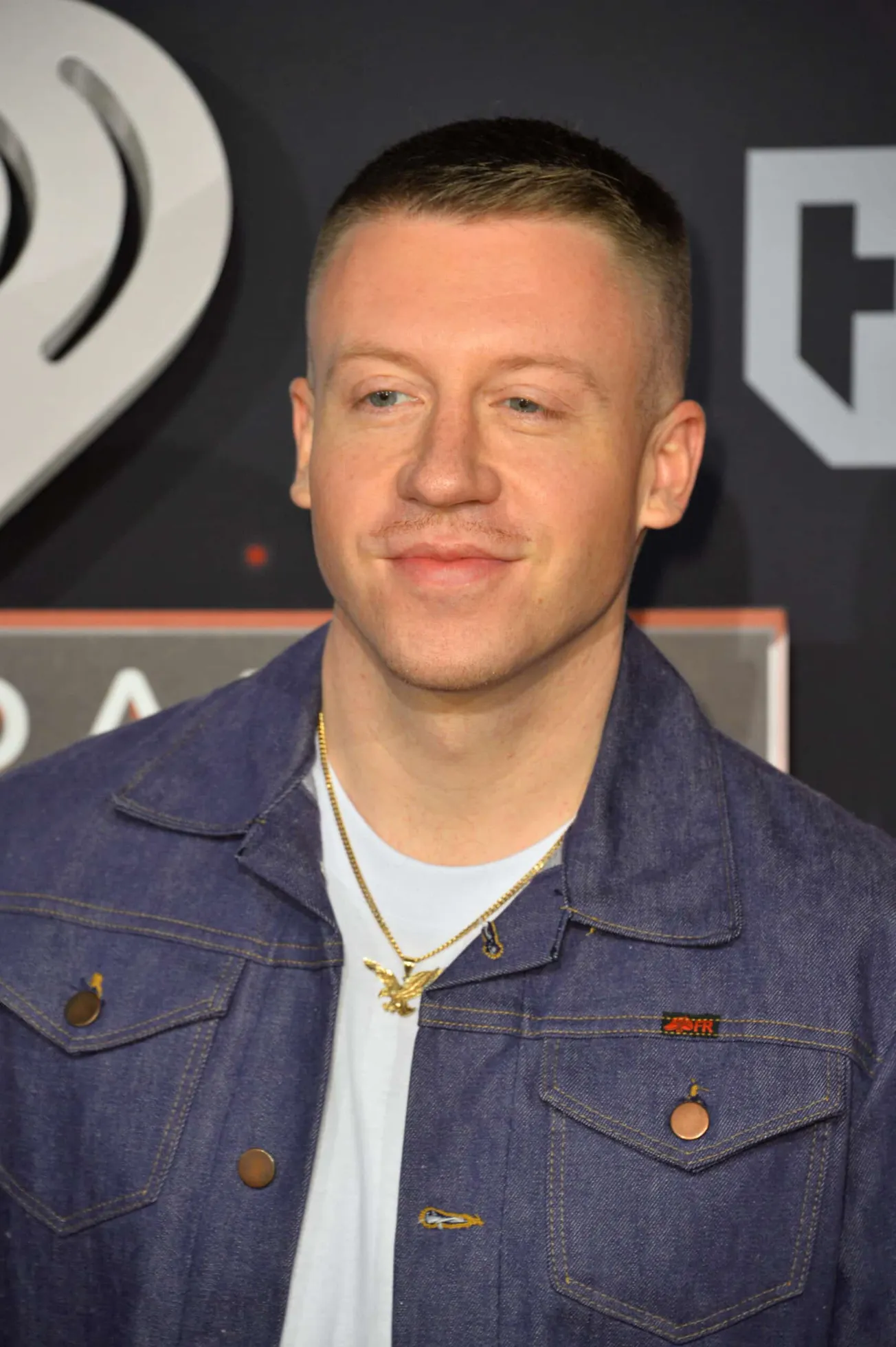 a close up fo Macklemore at a press event, smiling