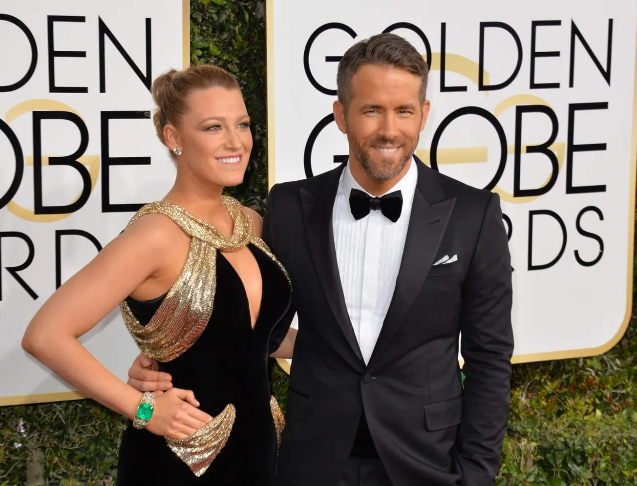 Blake Lively and Ryan Reynolds on the red carpet at the 2017 Golden Globe Awards. She wears a black and gold sleeveless dress