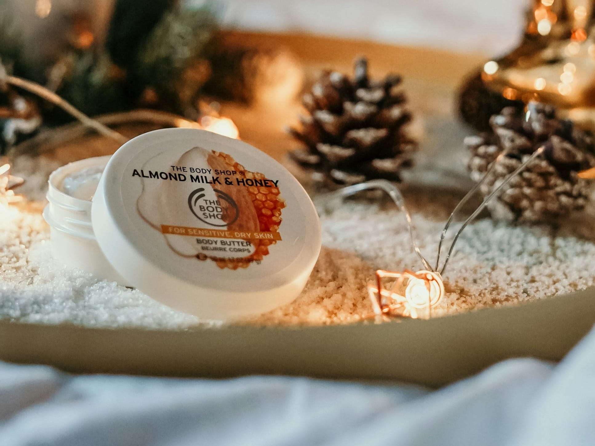 lit candle near pine cone and cosmetic case