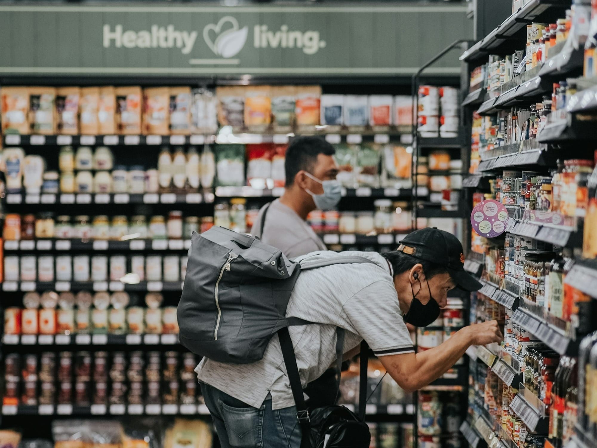 man in gray polo shirt and blue denim jeans standing on grocery store
