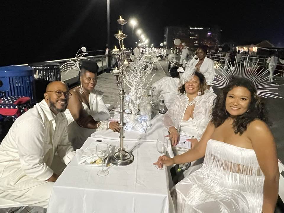 Von Purnell, of Trenton, (Left Front) Jessica Stewart, of Merchantville, (Right Front) Helen Jones-Walker, (Left second chair) also of Merchantville and Adrienne King, (Righn second chair) of Willingboro, set an exquisite table with a tall silver candle holder and frosted white centerpiece. Photo Credit: Mark Tyler