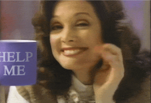 GIF of a woman holding a mug that says 'Help Me' on it