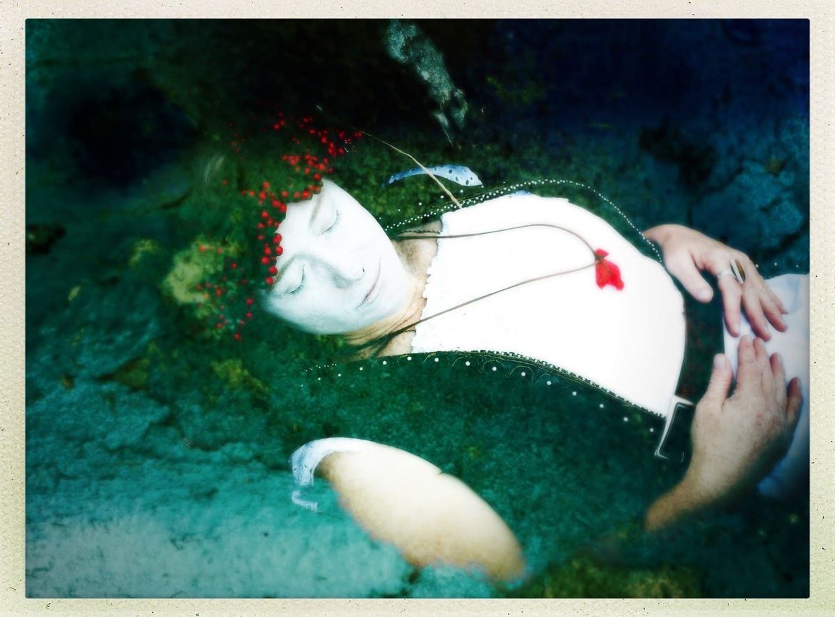Image of Huia, pale faced as if dead, merging with the landscape a photograph she entitled "Initiation"