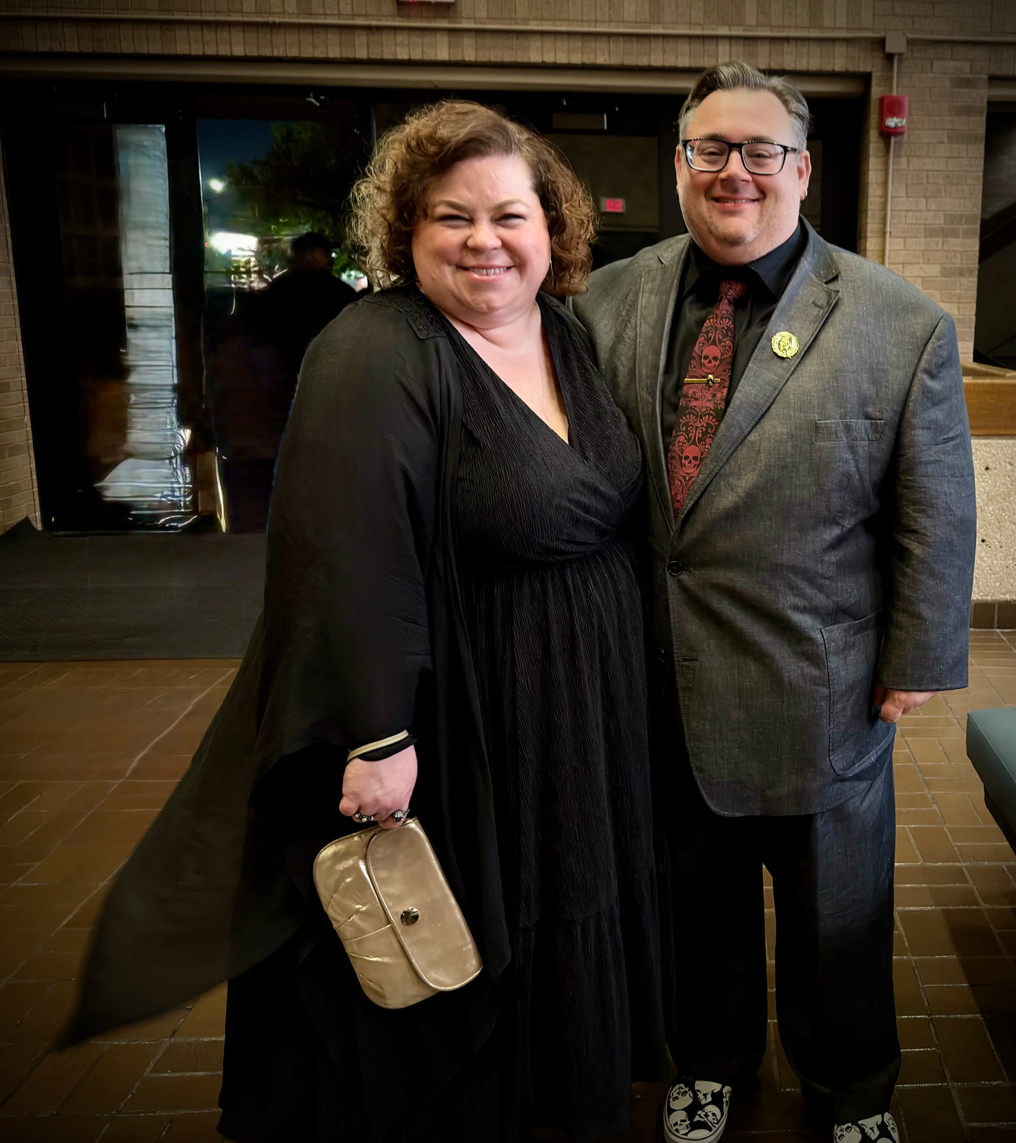 Mike and his wife Ali dressed up for the show. Ali is wearing a black dress and a flowy sweater. Mike is wearing a suit, and decked out with skull accessories.