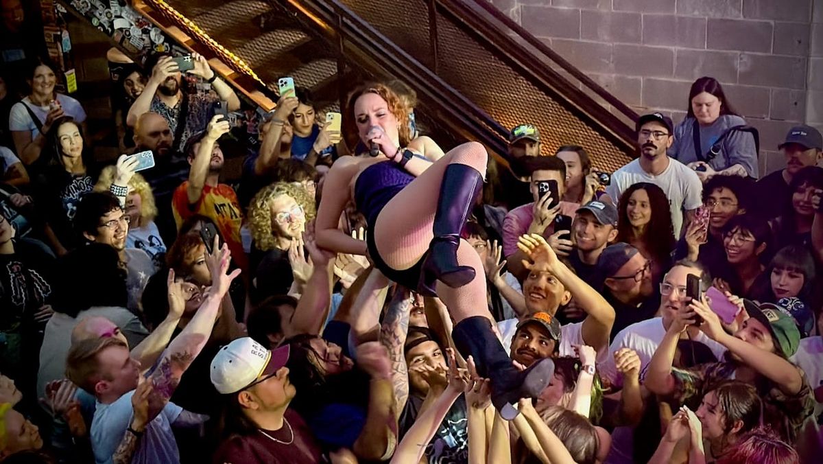 Christine Goodwyne of Pool Kids crowd surfing while singing.