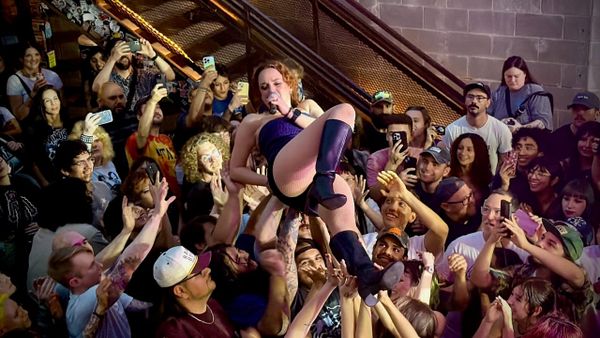 Christine Goodwyne of Pool Kids crowd surfing while singing.