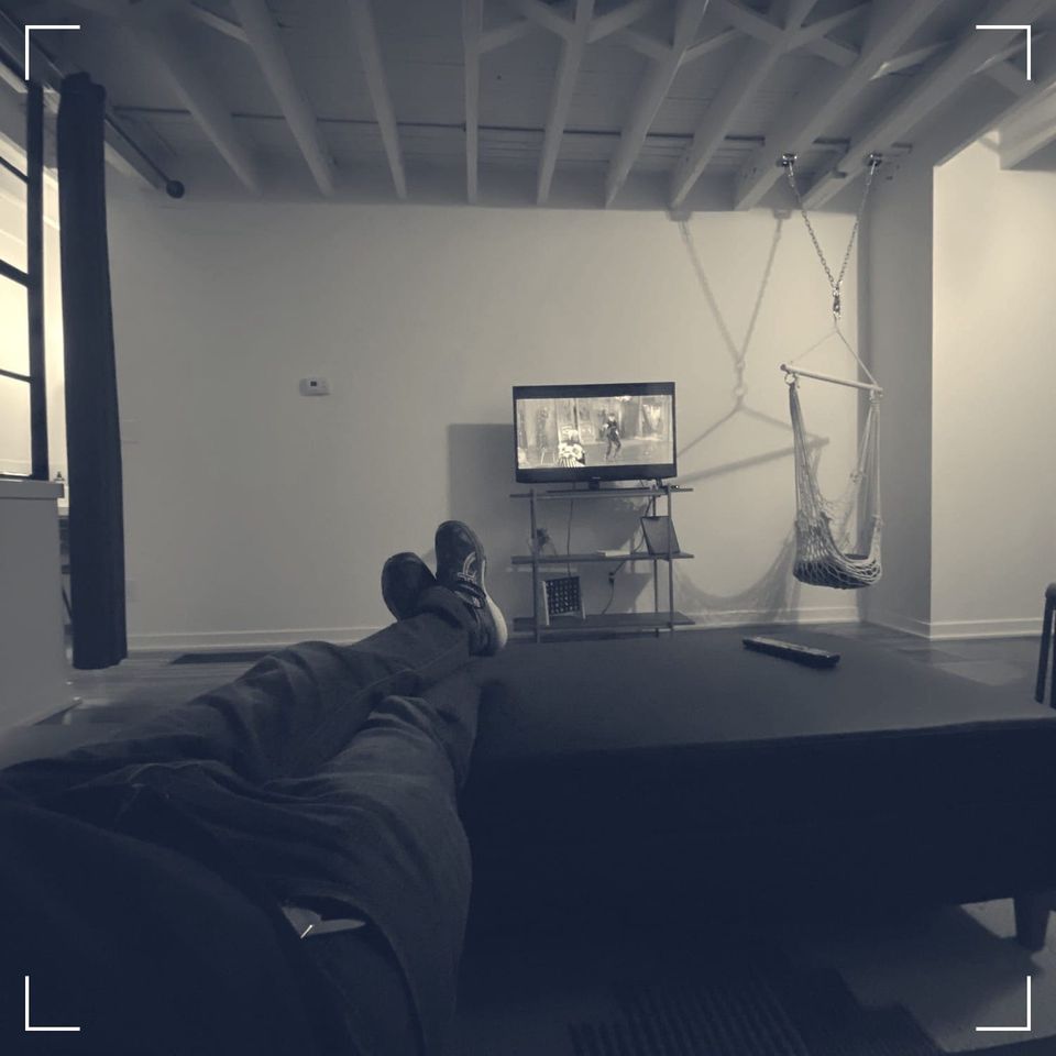 feet up on a tv table in an otherwise vacant apartment, watching a small tv