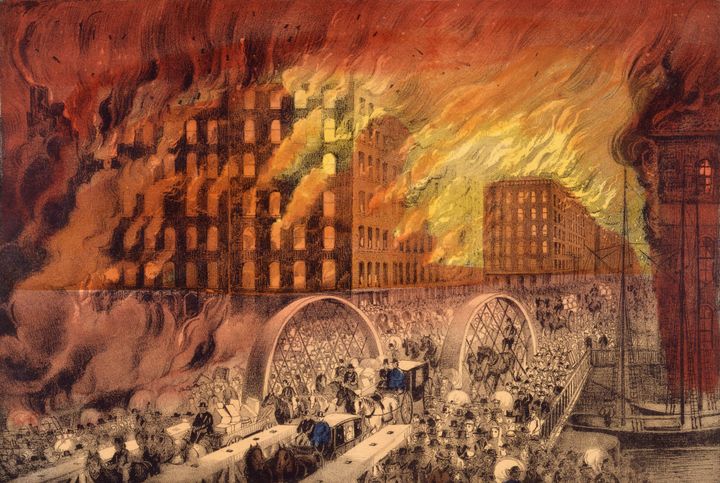 A color lithograph of Chicago burning in October 1871, with crowds, wagons, and carriages fleeing across a bridge under a sky of flame.