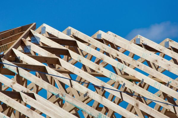 Rohbau eines Einfamilienhauses mit offenem Dachstuhl auf einer Baustelle bei Tageslicht