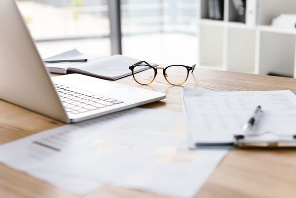 Schreibtisch mit Laptop, Brille und Unterlagen – Symbolbild für das genaue Prüfen von PKV-Tarifen