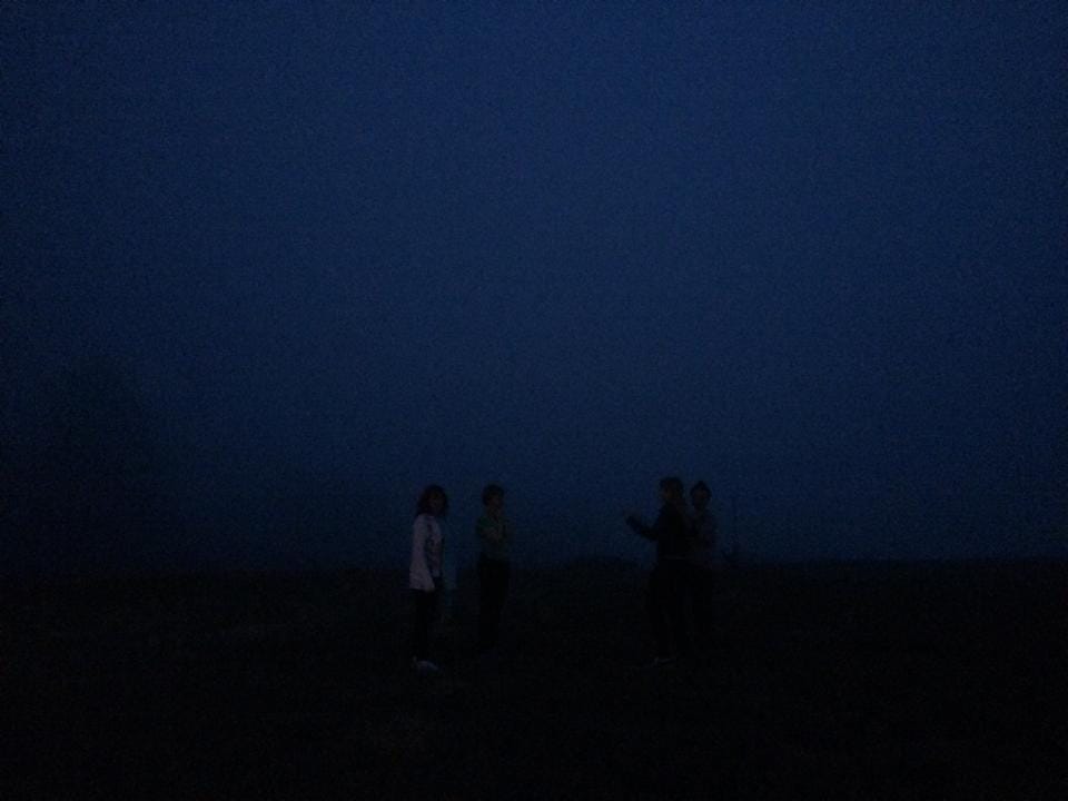 [A deep blue haze of fog in the night. Through the haze some shadowed figures can be made out.]