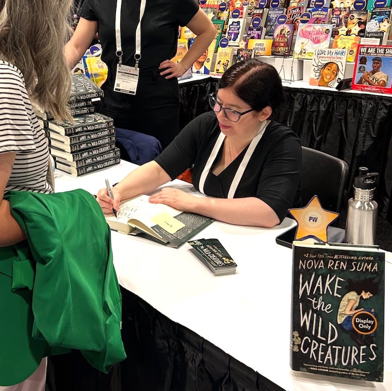 [Photo of Nova Ren Suma signing a copy of Wake the Wild Creatures at the Little, Brown Young Readers booth.]