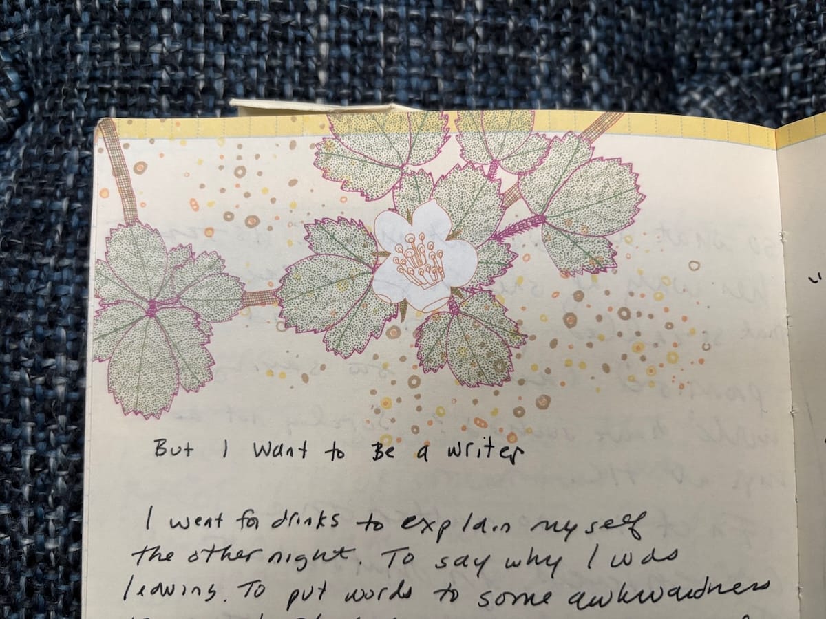 Page from a notebook with green leaves and a white flower printed on the page. Text in sloppy blank ink says: "But I want to Be a writer / I went for drinks to explain myself the other night..." etc.
