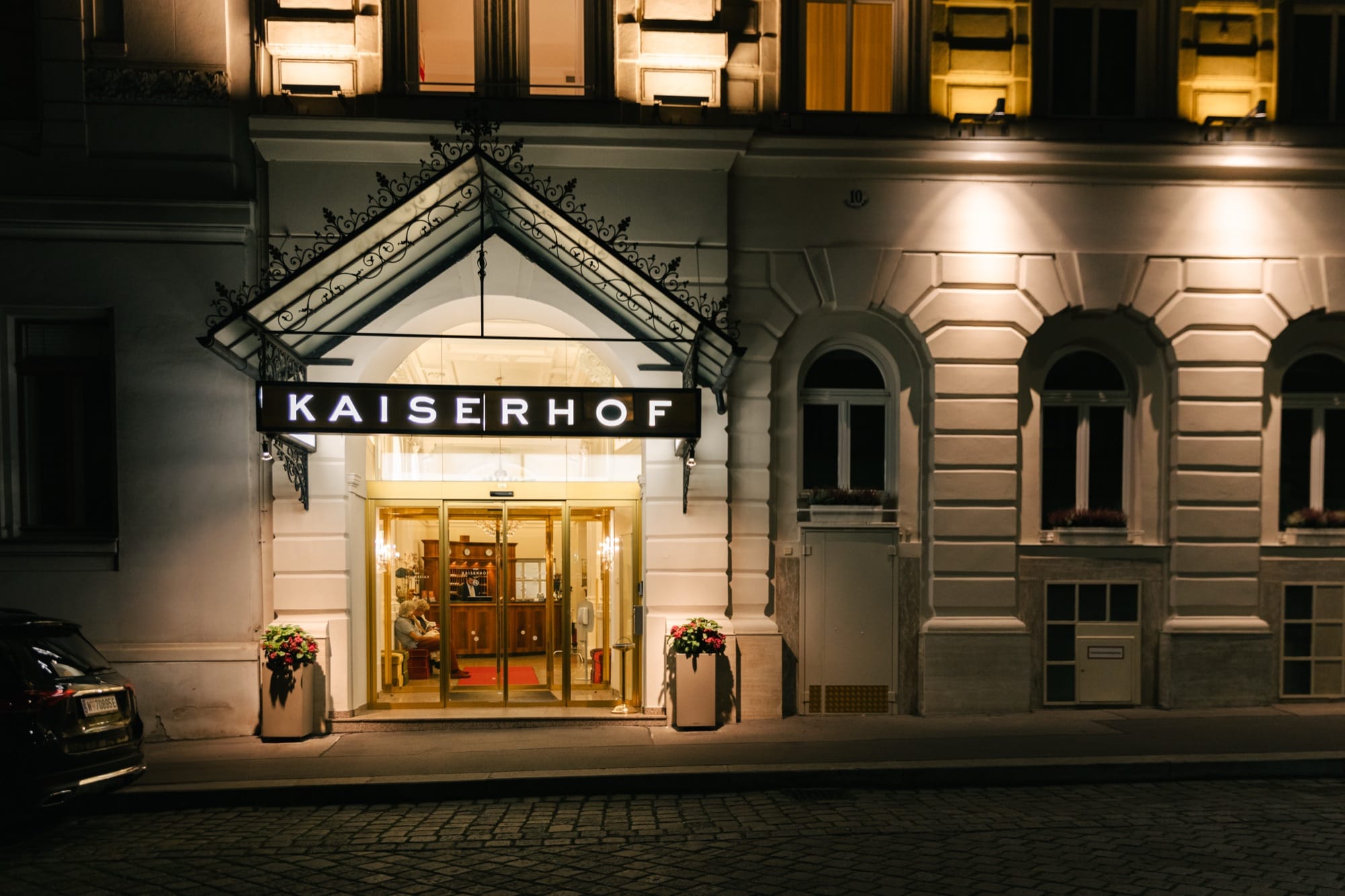 Beleuchtete Fassade und Eingang des KAISERHOF Wien mit Vordach und Schriftzug am Abend