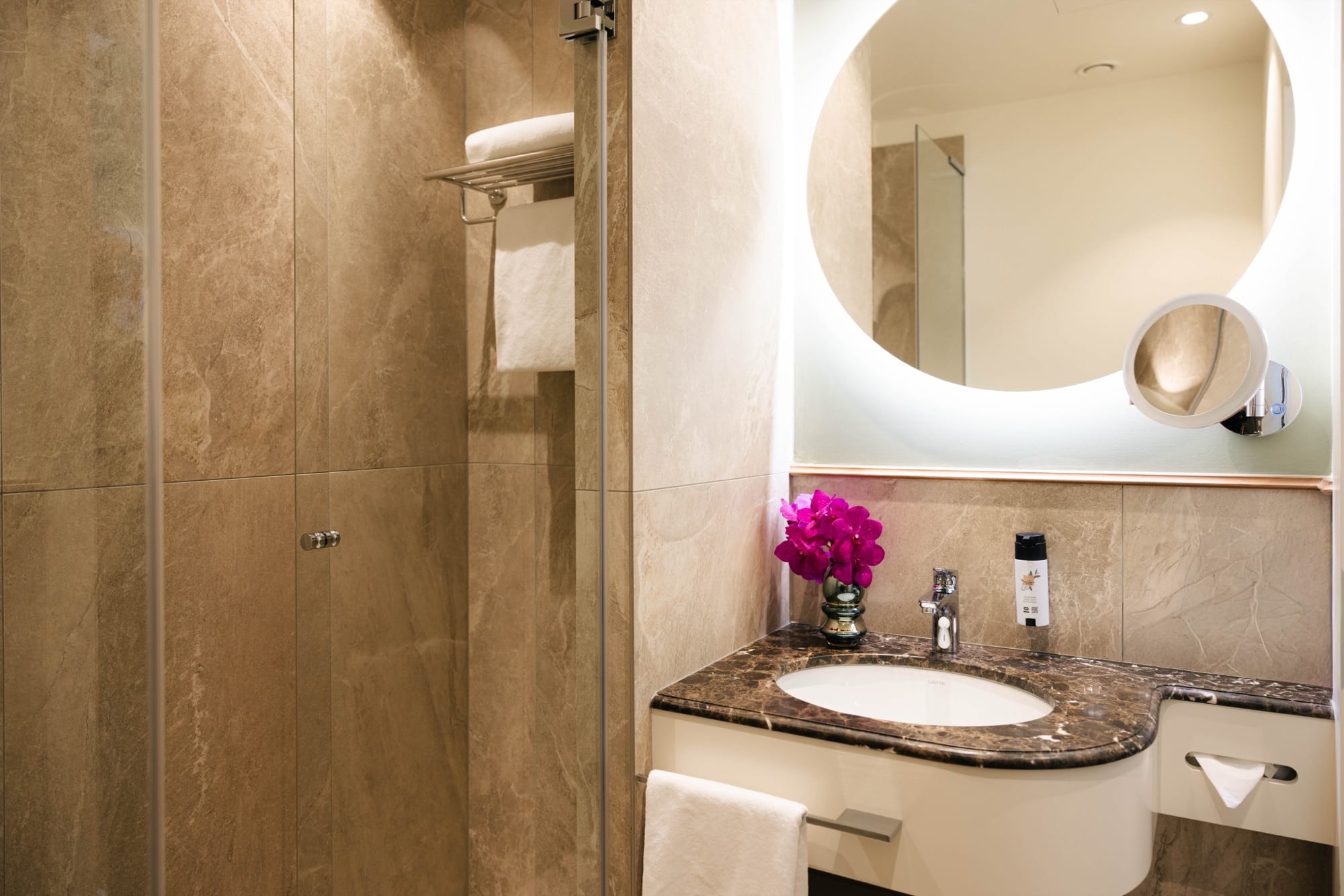 Badezimmer mit Walk-in-Dusche, Marmorwaschtisch und beleuchtetem runden Spiegel