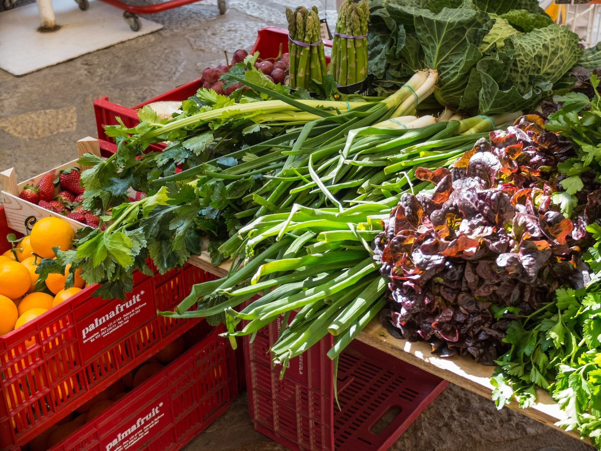 Kisten mit Orangen, Frühlingszwiebeln, Salat und Kohl vor einem Laden in Fornalutx