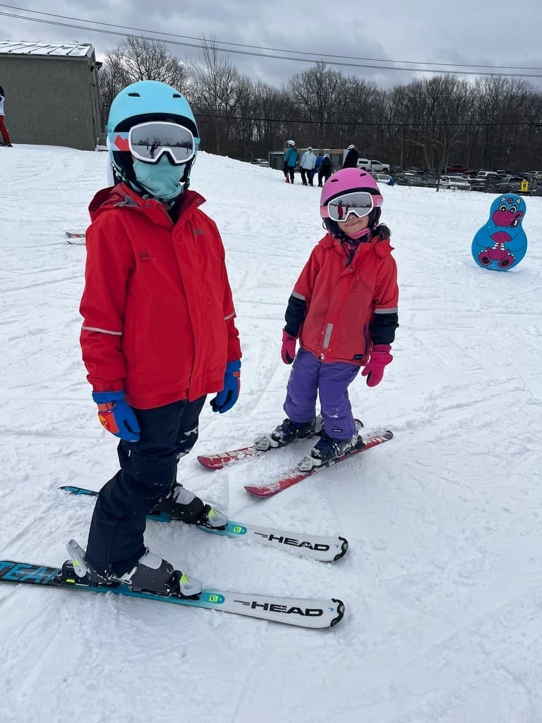 Two kids bundled up and on their skis