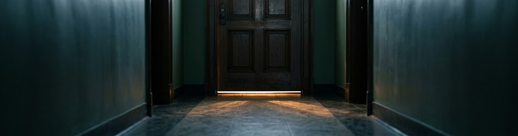 A closed panelled door with light spilling underneath