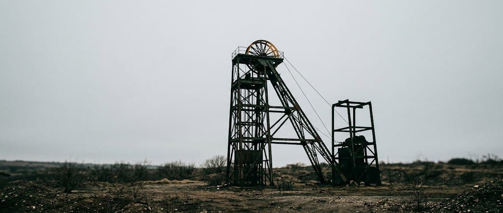 A mine headframe silhouetted against an overcast sky