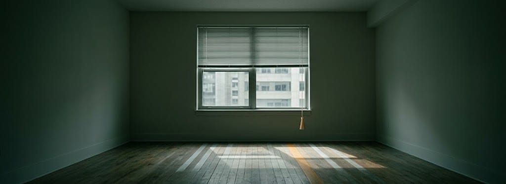 A window blind half drawn in an empty room