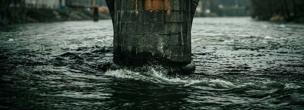 A stone bridge pier standing firm in moving water