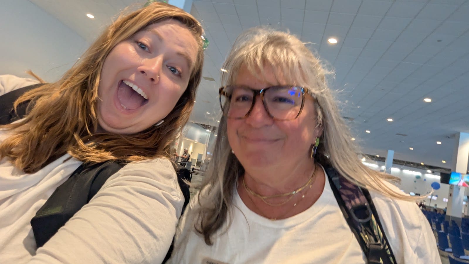 Two Somewhere Beyond Vacations travel advisors taking a joyful selfie in the cruise terminal before boarding