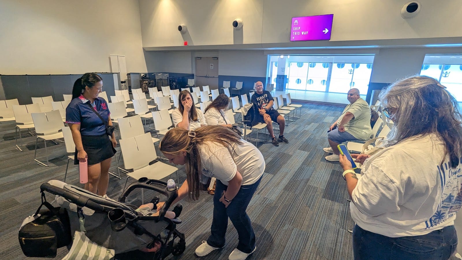 Somewhere Beyond Vacations travel advisors and their families waiting in a cruise terminal, one advisor tending to a baby in a stroller