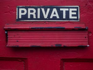 A sign which reads 'private' above a red letterbox on a red door