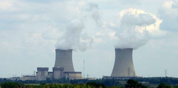 Just Solutions article by Arjun Makhijani featured image of two smoke stacks in the distance