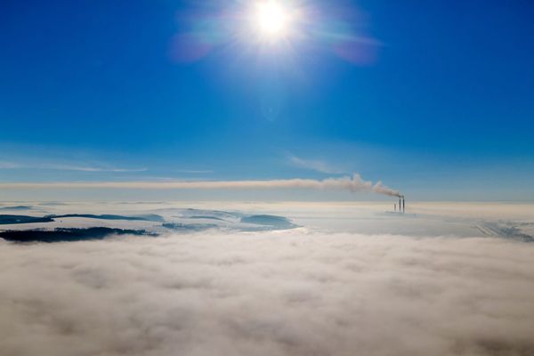 Just Solutions article by Arjun Makhijani featured image of smoke stacks in the distance