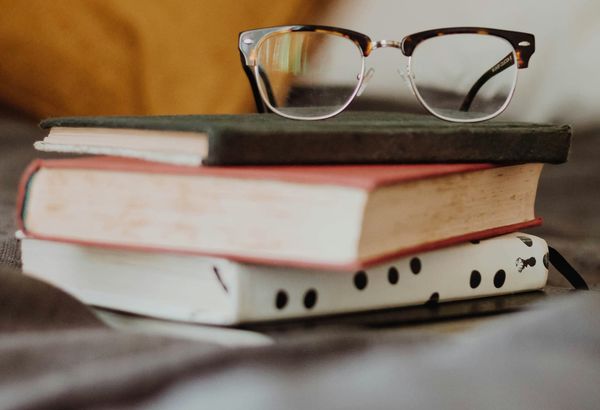 Two books in a pile with a pair of eyeglasses on top