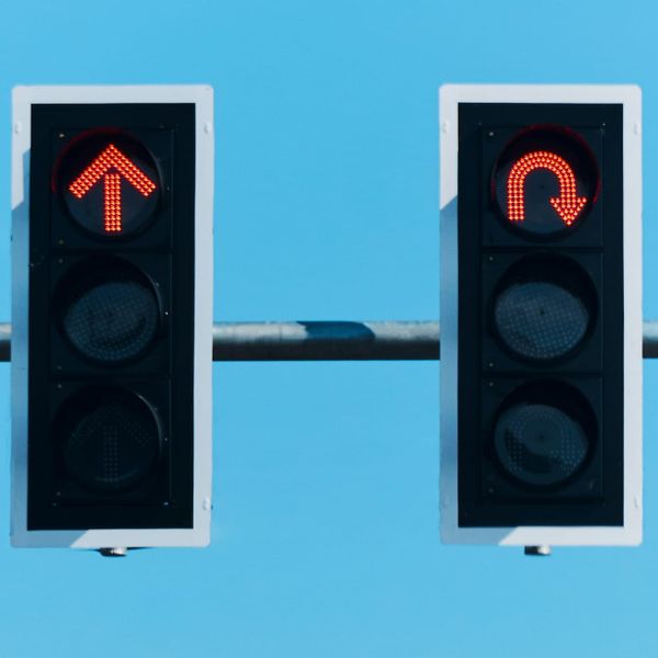 two stop lights one with red arrow pointing ahead and one with curved arrow bending behind