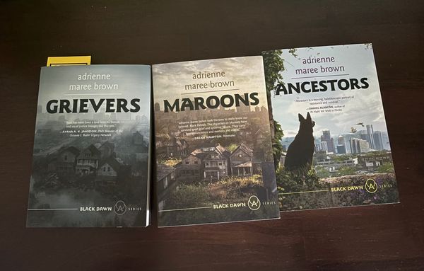 black backgroun, three books - the Grievers Trilogy by adrienne marie brown. 