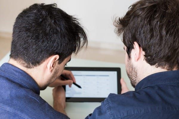 Two people reviewing auto insurance comparison results on a tablet screen