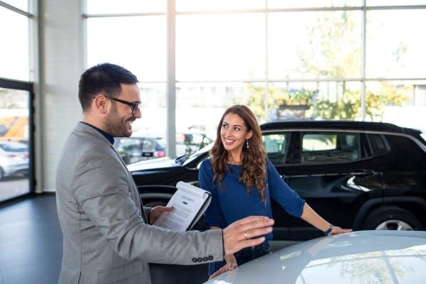 Car dealer explaining lease terms to a customer at a dealership showroom