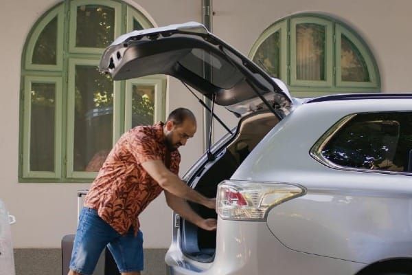 Man loading luggage into a white SUV, representing a move across states and auto insurance changes