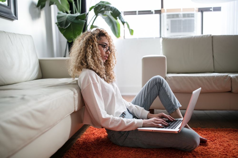 A woman sitting on the floor while working on her laptop