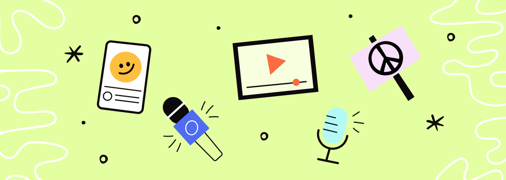 A phone with a smiling face, a microphone, a tablet playing a video, another microphone, and a peace sign made of cardboard