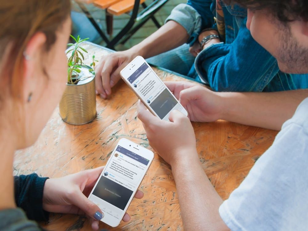 three people and two of them looking at their phone