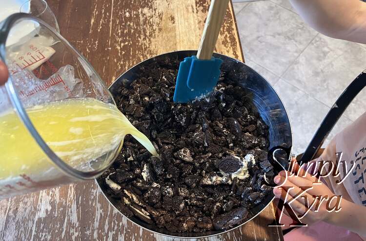 Pouring a jug of melted butter into the Oreo cookies. 