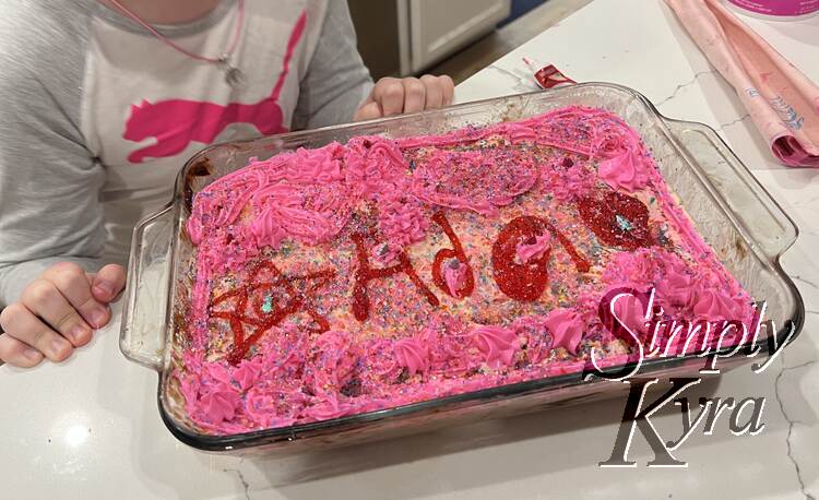 Ada posing next to her pink and red “Ada” cake. 