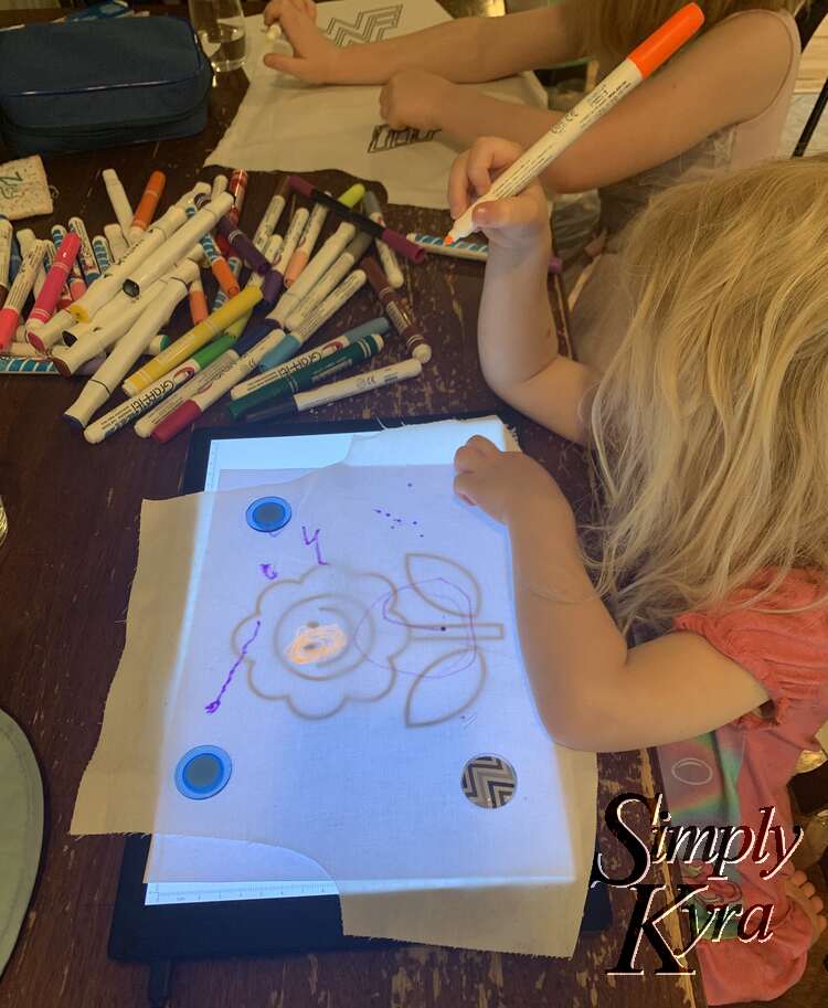 Zoey tracing a printed flower coloring Sheed onto fabric using a Lightbox. 