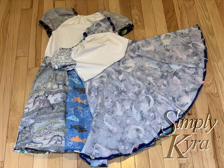 Image shows two dresses laid out on the floor inside out showing the seams. 