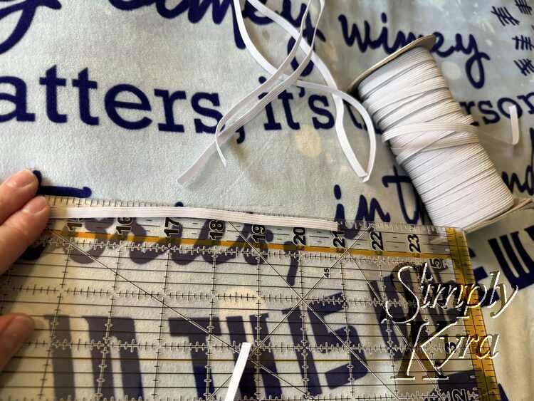 Image shows the roll of elastic with several cut off near the top and one laid out against the quilting ruler showing 21 inches long. 