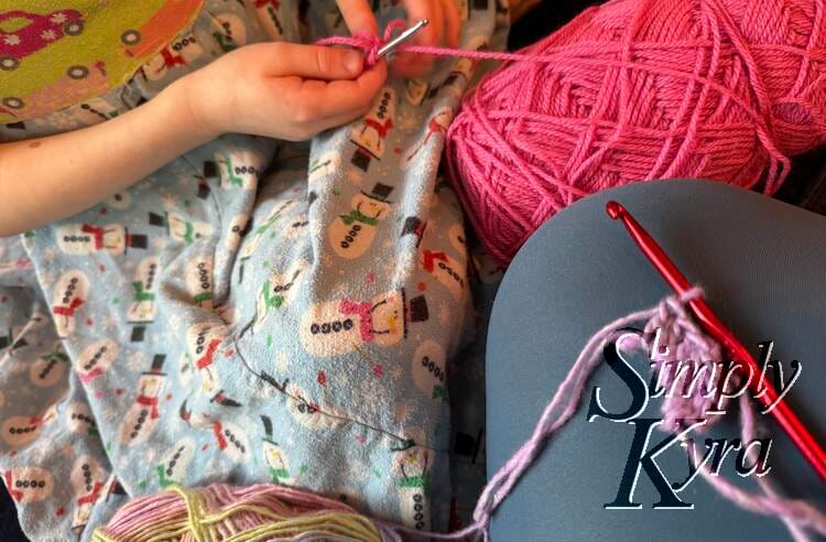 Image shows our legs and yarn as we work on our own projects.
