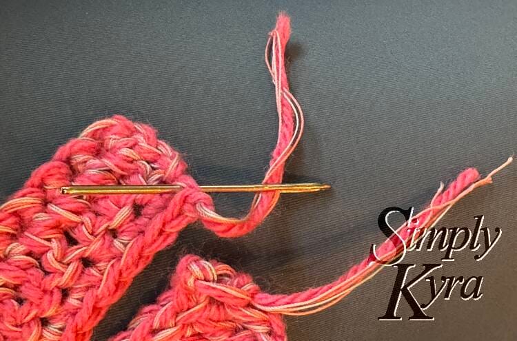 Image shows either end of the scarf with a sewing needle trapping the one end to weave it in.
