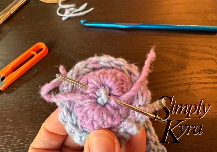 Image shows the inside of the hat with the yarn already brought through it all once and the needle poised to do it again.
