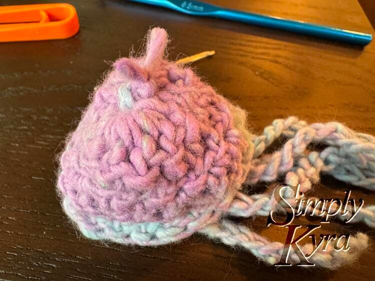 Image shows the hat inside out resting on the table with the hair going off to the right and the top knotted.
