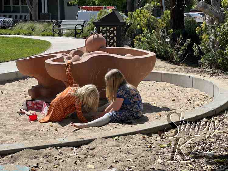 Image shows the girls digging for the 'wet' sand in front of the turned off water feature.